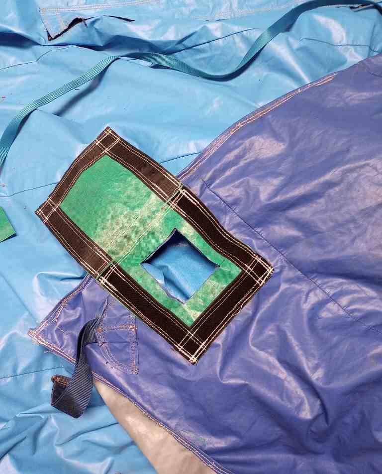 Reinforced patch stitched over a tear in blue inflatable vinyl